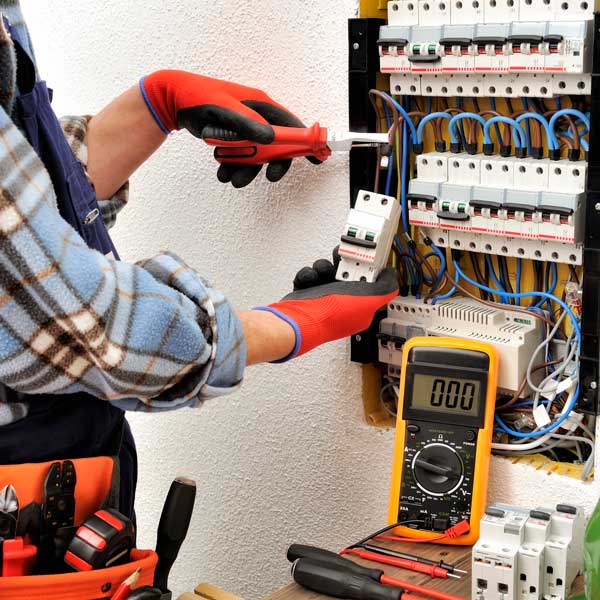 hands in frame repairing electric panel with help of multimeter