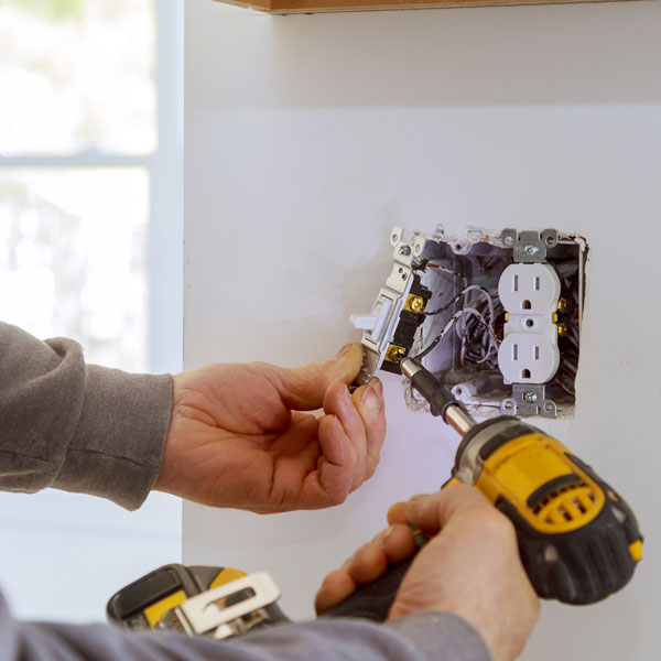 man opening and repairing electric socket with help of driver